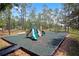 Community playground with swings, slide and benches surrounded by trees and green turf at 426 Prestwick Dr, Davenport, FL 33897