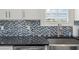 Granite counter with stainless sink and stylish backsplash with natural light peering through shuttered window at 438 Water St # 438, Celebration, FL 34747