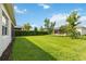 Lush backyard features an expanse of green grass, trees, and a tidy perimeter of hedges at 5009 E Fountainwood Dr, St Cloud, FL 34772
