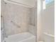 Bright bathroom featuring a tiled shower and bathtub combination with handrails and a built-in toiletry shelf at 5009 E Fountainwood Dr, St Cloud, FL 34772
