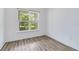 A sunlit bedroom with wood-look flooring and a large window offers a view of lush greenery at 5009 E Fountainwood Dr, St Cloud, FL 34772