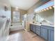 This bathroom features tiled floors, a tub, a glass shower, a large mirror and vanity with double sinks at 518 Brighton Dr, Davenport, FL 33897