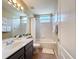This bathroom includes a tub with shower, a vanity, a toilet, a window, and a mirror with a lighting fixture at 518 Brighton Dr, Davenport, FL 33897