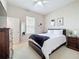 This bedroom has carpeted floors, a ceiling fan, a large bed with one bedside table and dresser and artwork on the walls at 518 Brighton Dr, Davenport, FL 33897