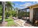 Landscaped backyard with tropical foliage and a screened-in lanai at 608 Grand Canal Dr, Poinciana, FL 34759