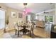 Bright dining area with a modern chandelier, glass table, and open view into the living room at 608 Grand Canal Dr, Poinciana, FL 34759