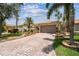 Home showcasing a brick driveway leading to a two-car garage, with lush landscaping and mature trees at 608 Grand Canal Dr, Poinciana, FL 34759