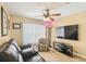 Cozy living room featuring a plush leather sofa, patterned armchair, and modern entertainment center with a large-screen TV at 608 Grand Canal Dr, Poinciana, FL 34759
