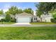 Charming single-story home with a two-car garage, lush green lawn, and manicured landscaping at 7013 Beargrass Rd, Harmony, FL 34773
