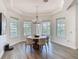 A sunlit dining room with tray ceiling, surrounded by large windows overlooking the lush backyard and swimming pool at 1211 Terralago Way, Kissimmee, FL 34746