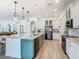 Open kitchen with a large island, pendant lights, stainless steel appliances, and white and green cabinets at 1211 Terralago Way, Kissimmee, FL 34746
