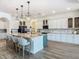A spacious kitchen featuring a large island with marble countertop, pendant lighting, and stainless steel appliances at 1211 Terralago Way, Kissimmee, FL 34746