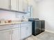 A functional laundry room featuring ample cabinetry, a sink, granite countertops, and modern washer and dryer units at 1211 Terralago Way, Kissimmee, FL 34746