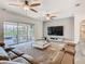 A spacious living room featuring a large sectional sofa, glass coffee table, and sliding glass doors to the outdoor living area at 1211 Terralago Way, Kissimmee, FL 34746