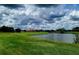 Scenic golf course view with lush green fairways, serene lake, and a distant view of the clubhouse against a cloudy sky at 13885 Arclid St, Orlando, FL 32832