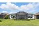 Landscaped backyard with an enclosed lanai, green lawn, and trimmed shrubbery offering a peaceful view at 142 Olympus Way, Kissimmee, FL 34759