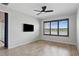 Modern bedroom featuring wood-look tile flooring, a ceiling fan and a mounted TV; an ideal retreat at 142 Olympus Way, Kissimmee, FL 34759