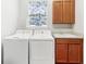 Functional laundry room with washer, dryer, utility sink, storage cabinets, and a window with decorative shade at 142 Olympus Way, Kissimmee, FL 34759
