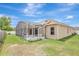 An inviting screened-in lanai attached to a stucco home with solar panels and a spacious backyard at 143 Brixham Ct, Kissimmee, FL 34758