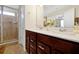 Bathroom featuring double vanity with white countertop, brown cabinetry, mirror and a glass-enclosed shower at 14389 Lanikai Beach Dr, Orlando, FL 32827