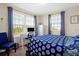 Cozy bedroom with large windows, blue patterned bedding, and a desk space for work or study at 14389 Lanikai Beach Dr, Orlando, FL 32827