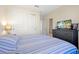 Comfortable bedroom features a window with blinds, nightstands and blue and gray stripped comforter at 14389 Lanikai Beach Dr, Orlando, FL 32827