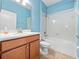 This bathroom boasts blue walls, a wood vanity, and a tub-shower combination with white tiling at 1470 Lake Side Ave, Davenport, FL 33837