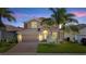 Charming two-story home with a tile roof, an arched entryway and a brick driveway, illuminated by outdoor lighting at 1470 Lake Side Ave, Davenport, FL 33837