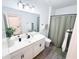 This modern bathroom boasts a large mirror, white vanity, and a shower with a neutral-colored curtain, offering a clean design at 1508 Bunker Drive Bunker, Davenport, FL 33896