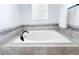 Modern bathtub with neutral tile surround, black faucet, and accent tile, providing a soothing spa-like atmosphere at 1508 Bunker Drive Bunker, Davenport, FL 33896