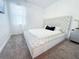 Bright bedroom featuring a stylish bed with white tufted headboard, plush carpeting, and large window with sheer curtains at 1508 Bunker Drive Bunker, Davenport, FL 33896