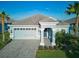 Charming single-story home featuring a paver driveway, a two-car garage, and lush tropical landscaping under a bright blue sky at 1508 Bunker Drive Bunker, Davenport, FL 33896