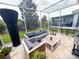 This screened patio features comfortable gray outdoor furniture, a coffee table, and views of the manicured backyard and green space at 1508 Bunker Drive Bunker, Davenport, FL 33896