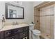 Well-lit bathroom featuring a dark vanity, stone countertop, framed mirror, and a tiled shower with mosaic accents at 1712 Melvin Ave, Orlando, FL 32806