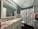 Bathroom features a stylish vanity with a granite countertop and a decorative shower curtain at 2410 Sweetwater Blvd, St Cloud, FL 34772