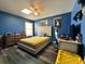 Cozy bedroom featuring wood floors, blue walls, ceiling fan and natural light at 2410 Sweetwater Blvd, St Cloud, FL 34772