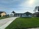 Charming single-story home with lush green lawn, palm trees, and a long concrete driveway at 2410 Sweetwater Blvd, St Cloud, FL 34772
