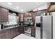 Modern kitchen with stainless steel appliances, dark wood cabinets, and granite countertops at 2454 Quail Run N Blvd, Kissimmee, FL 34744