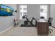 Well-lit office space with modern desk, exercise bike, shelving, and ample natural light at 2679 Ridgetop Ln, Clermont, FL 34711