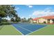 Community tennis court next to a pond and mature trees under a blue sky at 2826 Club Cortile Cir # B, Kissimmee, FL 34746