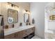 Bright bathroom features a double sink vanity with modern fixtures, stone accents, and framed mirrors at 2851 Wagon Ct, St Cloud, FL 34772