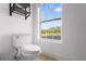 Bright bathroom with a white toilet, shelving, and a window providing natural light and views at 2851 Wagon Ct, St Cloud, FL 34772