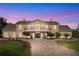 Elegant two-story home highlighted against the colorful evening sky, with beautiful landscaping and a circular driveway at 2851 Wagon Ct, St Cloud, FL 34772