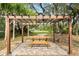 Wooden pergola with a picnic table on a brick surface surrounded by grass and trees at 2851 Wagon Ct, St Cloud, FL 34772