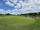 An immaculate golf course with a blue flag blowing in the wind provides a premier amenity at 3349 Schoolhouse Rd, Harmony, FL 34773