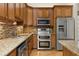 Kitchen with stainless steel appliances, wood cabinets, granite countertop, mosaic tile backsplash, and hardwood floors at 3349 Schoolhouse Rd, Harmony, FL 34773