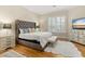 Comfortable main bedroom featuring hardwood floors, a tufted headboard and natural light from the windows at 3349 Schoolhouse Rd, Harmony, FL 34773