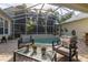 Enclosed patio area with brick pavers, comfortable seating, and a refreshing swimming pool with lush, tropical landscaping at 3349 Schoolhouse Rd, Harmony, FL 34773