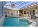 Inviting enclosed pool area with brick pavers, outdoor kitchen, lush tropical landscaping, and solar panels at 3349 Schoolhouse Rd, Harmony, FL 34773