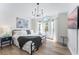 Bright bedroom features a chandelier, wood flooring, and a queen bed with many windows at 344 High Point Dr, Davenport, FL 33837